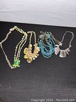 Four different styled women's necklaces displayed on black fabric, showing details of beads, pendants, and chain links.