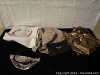 Top view of the lot showing all items including purses, fanny pack, hat, and bracelet arranged on black surface