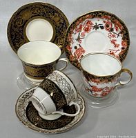Photo showing both vintage espresso cup and saucer sets with close detail on ornate patterns and gold trim.