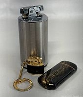 Photo showing all three lighters: large Ronson, small gold-tone keychain lighter, and black crackle patterned lighter together