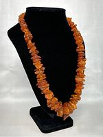 Amber necklace displayed on black stand showing full length and bead detail.
