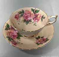 Front view of the teacup on the saucer showing floral pattern and gold-rimmed edges.