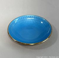 Small blue guilloche enamel dish with gold-tone rim, showing vibrant color and pattern.