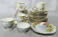 Full set of vintage Paragon dinnerware including stacked plates, cups on saucers, sugar bowl, creamer and cookie plate, all showing the Cliffs of Dover pattern with gold trim