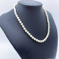 Front view of the Akoya pearl silver necklace displayed on a black bust.
