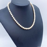 Front view of the Akoya pearl necklace displayed on a black necklace stand showing uniform pearl size and luster.