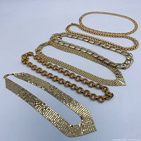 Six gold-plated necklaces laid out showing variety of chain styles including mesh, rope, and large link chains.