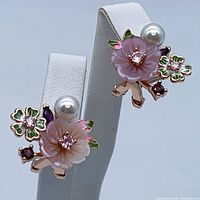 Front angled view of both earrings on white display stand