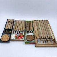 Front-facing photo showing all four sets of Japanese carving tools in their respective boxes and trays with wooden handles and various blade shapes.