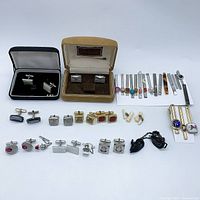 Overall grouping of cufflinks and tie clips on white background