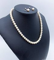 Genuine Japanese Akoya pearl necklace and earrings displayed on black bust form, showing necklace and clip-on style earrings with round white pearls.