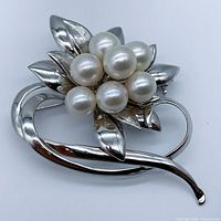 Front view of the silver brooch showing seven round Akoya pearls clustered above the leaf motif.