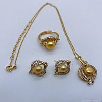 Full set: ring, earrings, and pendant necklace each featuring genuine golden pearls, clear stones, and 18K gold-plated metal
