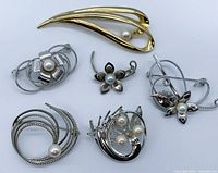 Top view of all six brooches showing overall design and pearl placements.