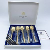Set of 5 gold plated coffee spoons in white box case with Givenchy logo lining, spoons are individually wrapped in plastic and laid on navy blue satin inside the box.