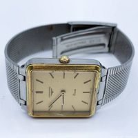 Angled view showing full watch with square case and mesh bracelet