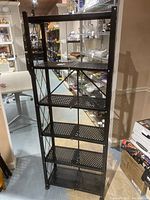 Front view of the black collapsible metal shelving unit showing six perforated shelves and cross-bracing on sides.