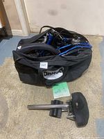 Folded Dahon bike packed in a black carrying bag alongside detached black seat and seat post resting on floor with instruction manual.