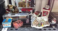 Photo showing various Disney collectibles including plush bears, tins, snow globes, a lighted village cottage, and small village pieces such as bridge and lamp posts.