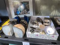 Overview of all stones, arrowheads, magnifier, glass sphere and framed print on table
