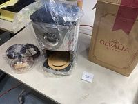 Gevalia coffee maker, glass carafe, and original box on table.