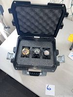 Open protective case showing three watches nestled in foam insert