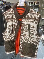 Front view of Sean John sleeveless vest with brown and cream pattern, orange interior lining, and brown pocket flaps.