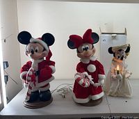 Wide shot of all three animated Christmas figures together on a table: Mickey, Minnie, and Angel Minnie