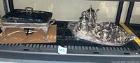 Photo showing silver plate chafing dish with ornate legs and Pyrex insert alongside Gorham silver plate tray holding coffee and tea pots, sugar and creamer bowls.