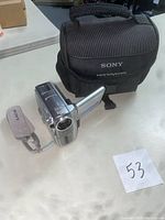 Sony Handycam DCR-PC109 camcorder with wrist strap and black Sony carrying case on white table