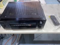 Sony STR-DB930 receiver on table with remote control wrapped in plastic beside it.