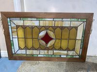 Front view of stained glass panel with red diamond motif in wooden frame