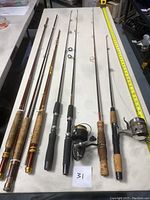 All seven rods laid flat showing handles, blanks and attached reels