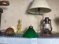 Photo showing all four lamps together on a shelf: tortoise lamp, yellow acrylic lamp, green glass pendant shade, and lantern style lamp with fabric shade
