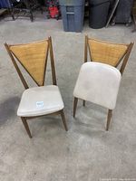 Pair of vintage Stackmore folding chairs. Shows wood frames with triangular cane backs and cream vinyl padded seats.