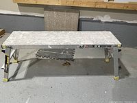 Folding scaffold platform showing metal foldable design with yellow safety caps on feet.