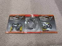 Three sealed packages of Moore picture hanging items laid out on a fabric surface, consisting of two Utility Hanger sets and one hanging wire set.