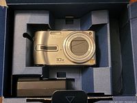 Panasonic Lumix DMC-TZ2 camera and charger set inside original box packaging with foam inserts