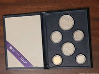 Six Canadian coins arranged in black Royal Canadian Mint presentation case with slots for each coin.