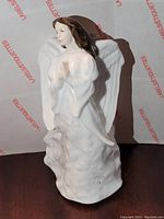Front view of Royal Doulton Christmas Angel figurine showing angel in praying pose in white robes with brown hair and detailed wings.