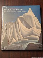 Front cover of the art book 'The Idea of North: The Paintings of Lawren Harris' in shrink wrap showing stylized mountain landscape.