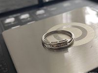 Engagement ring displayed on a metallic surface, showing the diamond channel setting and ring shape.