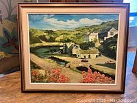 Framed oil painting showing a scenic countryside landscape with hills, buildings, a stone bridge, pond, and sky.