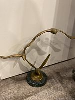 Front view of the brass birds sculpture showing three birds in flight mounted on a green marble base.