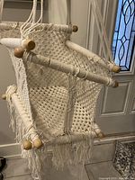 Front angle showing the crocheted cotton seat with fringe and wooden rods wrapped in rope.