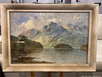 Front view of the framed painting depicting a mountainous landscape and lake.
