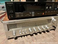 Photo showing front panels of two receivers stacked: silver Realistic STA-64B on bottom with tuning meter and control knobs, black Sony STR AV370 on top with digital display and buttons.