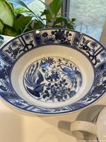 Close-up of large blue and white patterned porcelain bowl with floral and bird motifs.