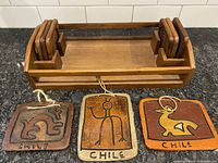 Teak serving tray with six coasters arranged in holder, and three signed Chile wall plaques placed in front.