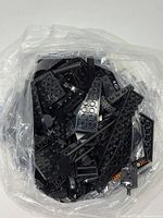 Overview of bag showing variety of black Lego bricks, plates, wedges and Technic parts